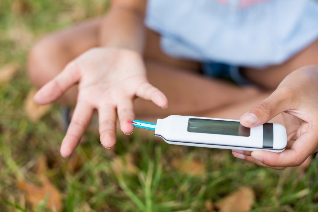 Girl testing diabetes on glucose meter