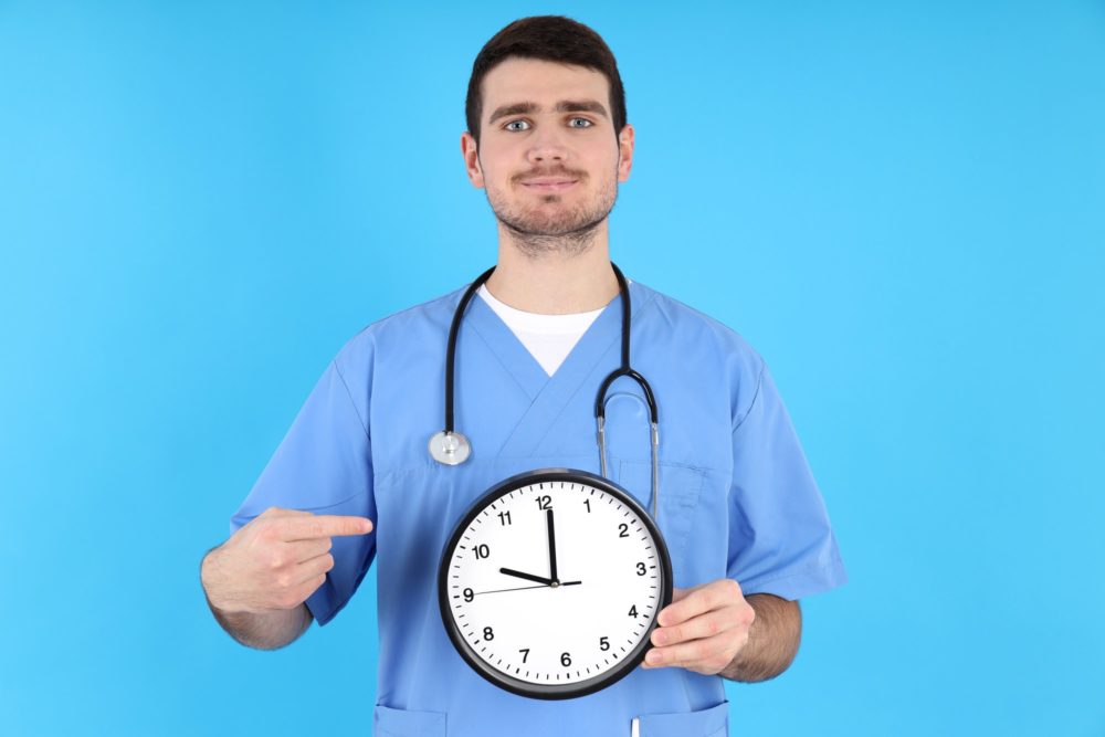 Male nurse with clock on blue background