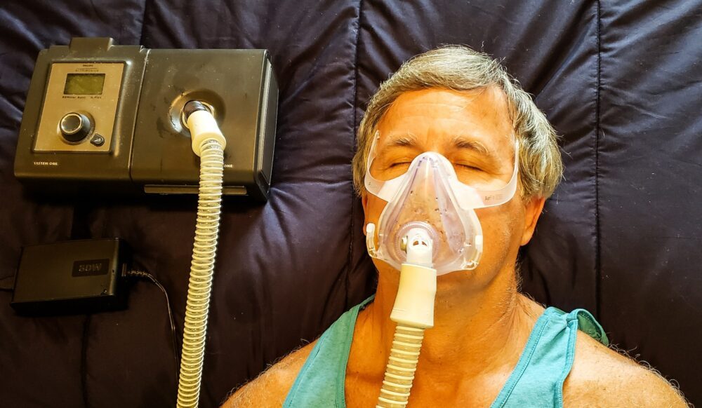 Man using breathing apparatus for sleep apnea in overhead health and medicine flat lay.