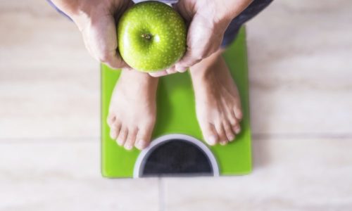 woman or man on a weight scale showing an apple and select his lifestyle - good nutition concept - Gout Attacks affect obese people